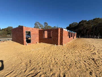 Inspector assessing brickwork quality and wall ties during a new build stage inspection in Perth